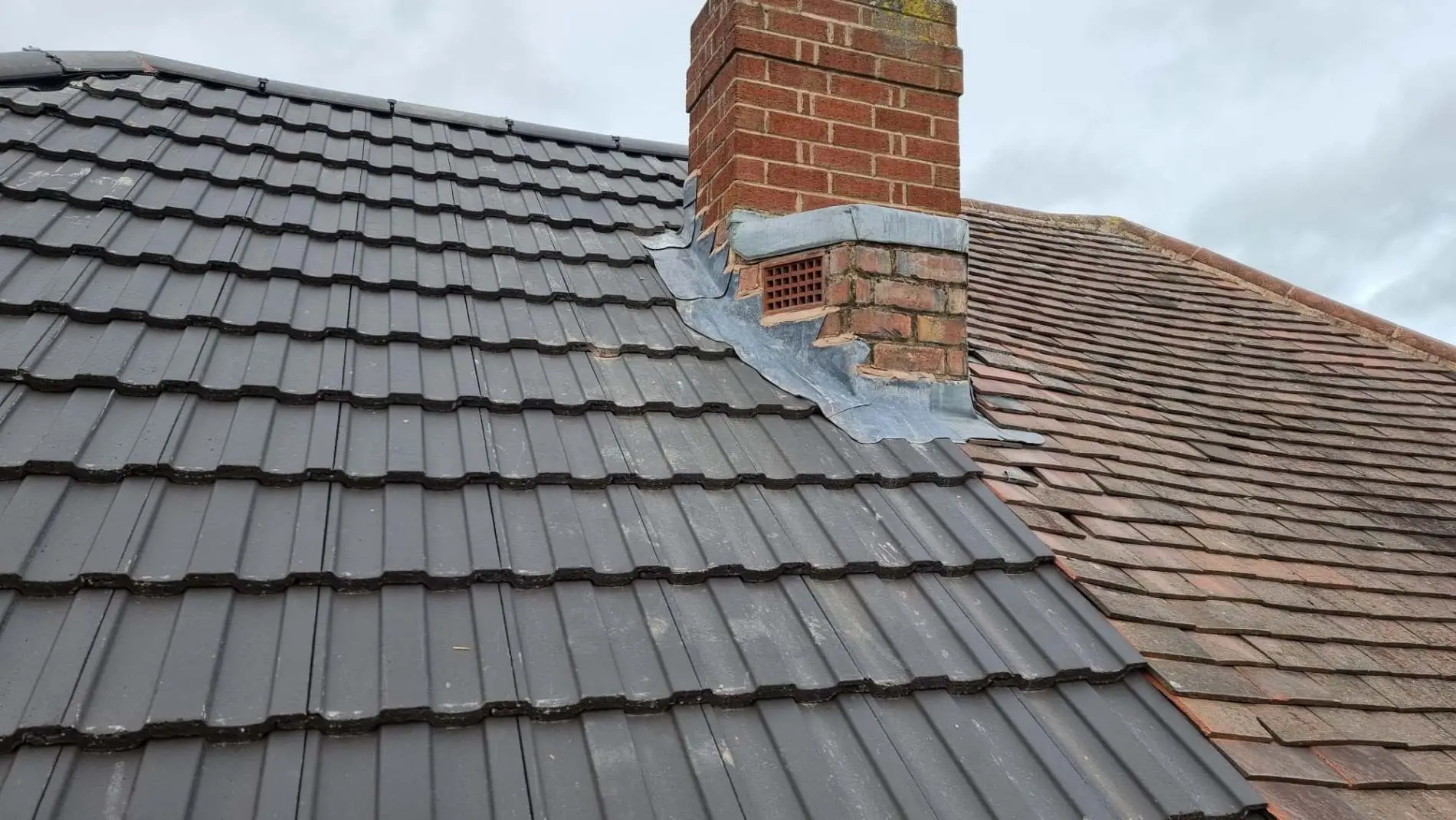Newly tiled grey roof with lead chimney flashing by Westridge Roofing Solihull